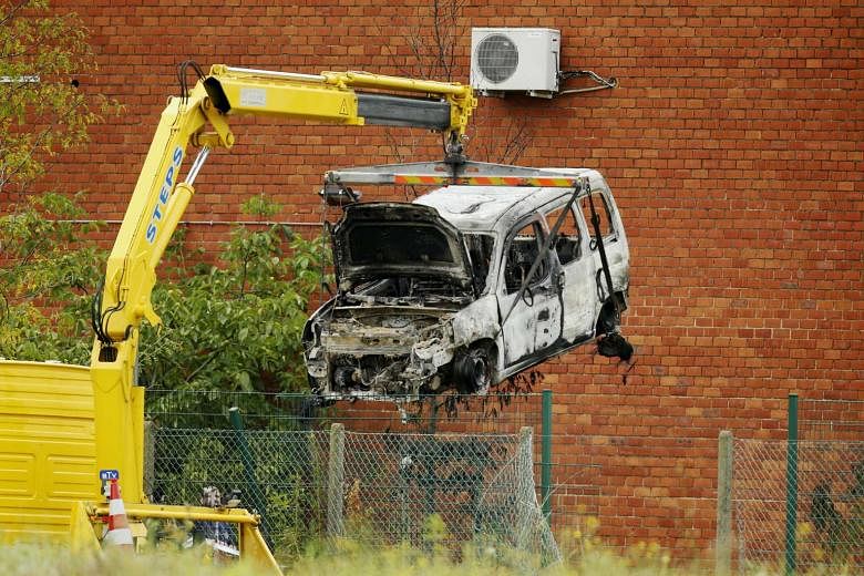 A burned-out car being lifted yesterday at the National Institute for Criminalistics and Criminology. Attackers rammed a car through the gates of the facility in Brussels and then started a fire. Part of the building was damaged in the fire. 