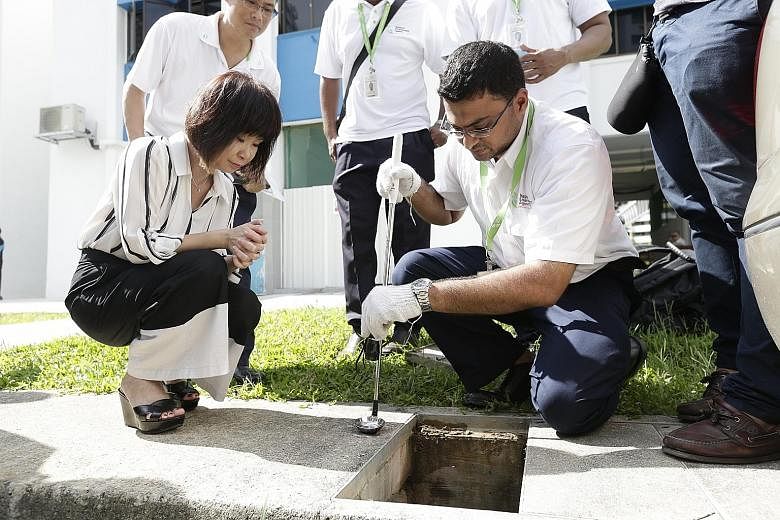 Senior Minister of State Amy Khor observing NEA officer Mohd Shah Al-Nawaz inspecting and treating a drain in Paya Lebar Way yesterday. Dr Khor said that while the Zika infection is less serious than dengue, the public still needs to be concerned bec