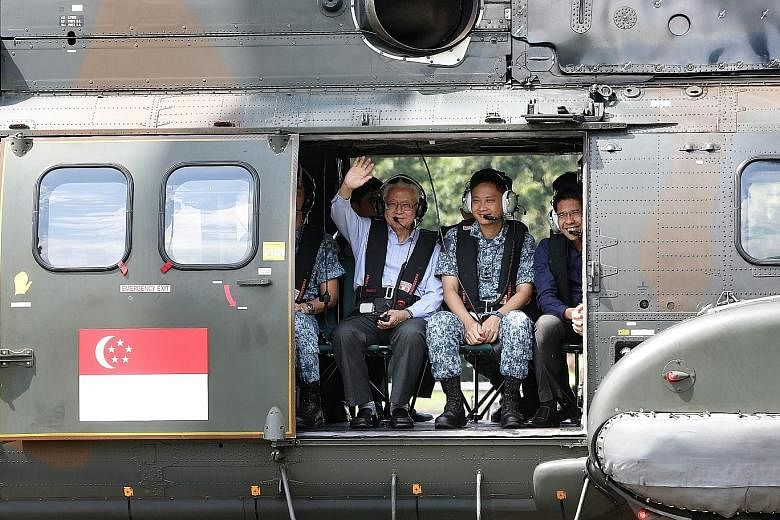 President Tan waving to the media during a ride in the Super Puma during his visit to the RSAF's Sembawang Air Base yesterday.