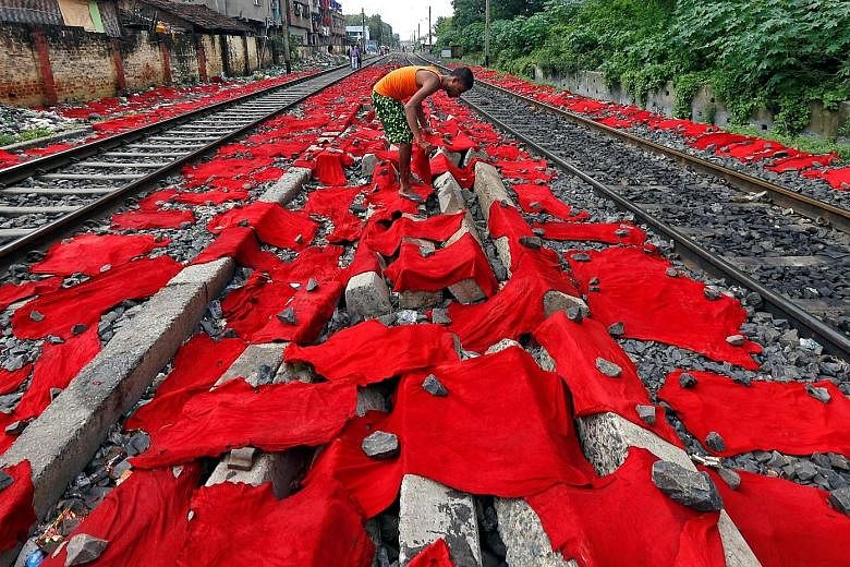 A tannery worker laying out dyed cattle skins for drying between railway tracks in Kolkata, India, yesterday. Cow skins are later treated with chemicals to make leather goods, while buffalo skins are used in machinery. Hundreds of small, family-owned
