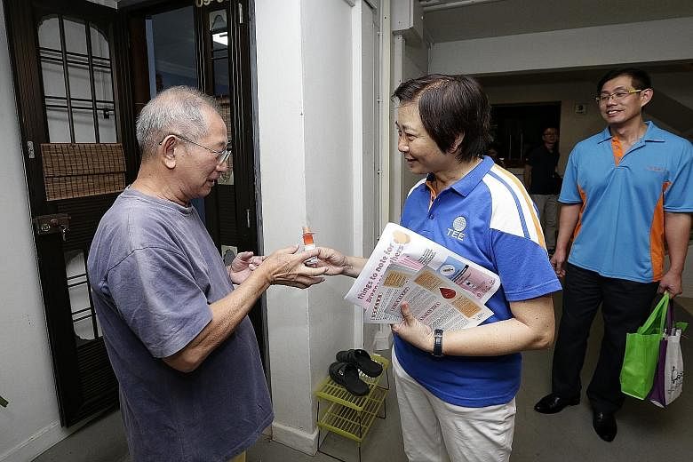 Nee Soon GRC MP Lee Bee Wah giving insect repellent to 71-year-old retiree Goh Han Kiat during her door-to-door visit at Block 826, Yishun Street 81, yesterday.