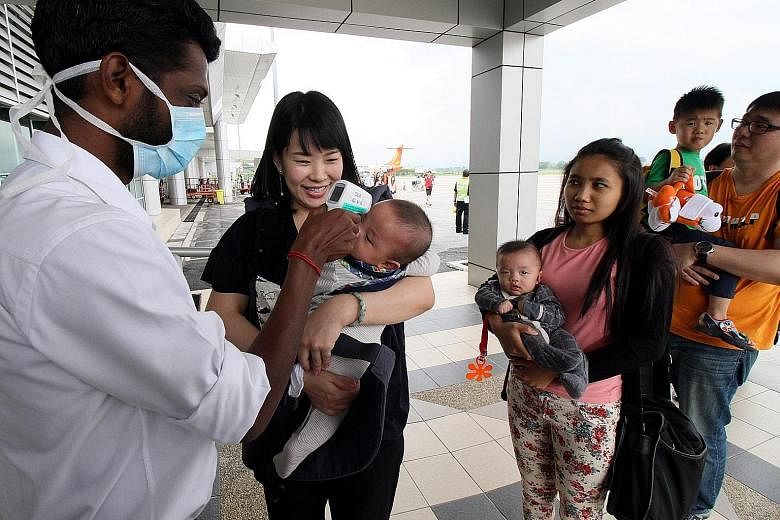 Malaysian health department staff conduct body temperature checks on passengers of a Firefly flight from Singapore at the Sultan Azlan Shah Airport in Ipoh, as part of precautionary measures to screen for the Zika virus.