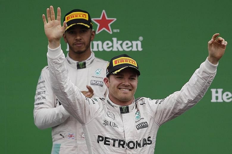 Nico Rosberg acknowledges the cheering crowd upon winning the Italian Grand Prix while Lewis Hamilton looks on. The German clinched his seventh win of the season.