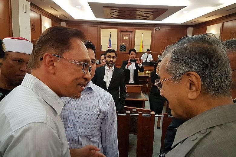 Dr Mahathir (right) meeting Anwar in court yesterday. They shook hands in a clear sign that old grudges paled in significance to a shared mission to take down Mr Najib over the 1MDB scandal.