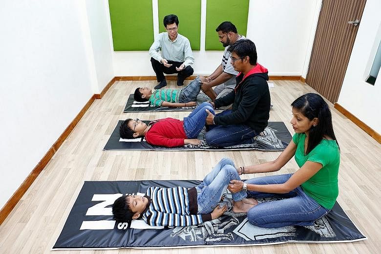 Parents assist their children as they perfom body movement exercises believed to stimulate brain development - part of the KidsBright programme by Care Corner Singapore for children with learning difficulties. The welfare organisation has offered thi
