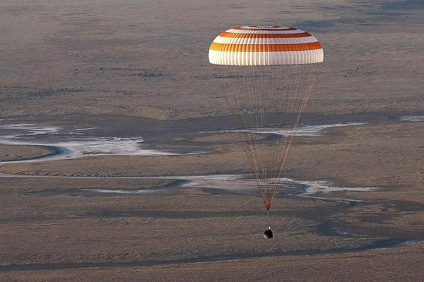 Disappearing into a layer of haze (above) as it approached the ground, the Soyuz TMA-20M spacecraft capsule carrying (left, from top) United States astronaut Jeff Williams, and Russian cosmonauts Oleg Skripochka and Alexey Ovchinin landed south-east 