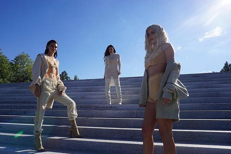 Reality TV star Kim Kardashian (centre) at her husband Kanye West's Yeezy 4 fashion show at Four Freedoms Park with her half-sisters Kendall (far left) and Kylie Jenner.