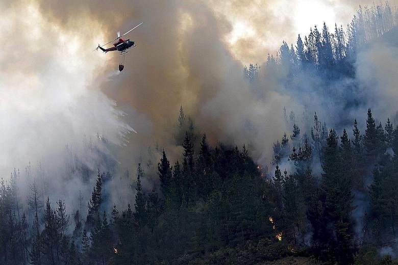 A helicopter dropping water on a forest fire near the village of A Fonsagra, in the Galicia region of north-western Spain, on Wednesday. The fire has already burned at least 80ha of forest.