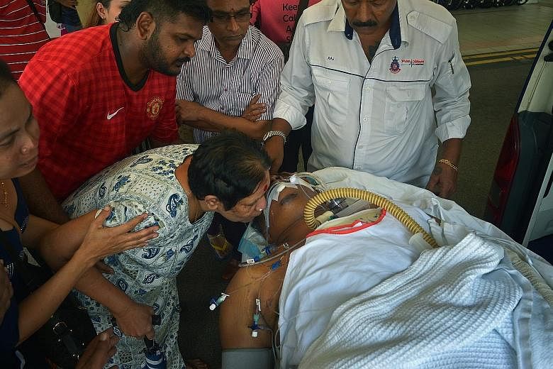 Above: Madam Thanabagiyam kissing her son, Mr Manokaran, as he was being wheeled into the emergency department at NUH yesterday. Left: Madam Muniandy, Mr Manokaran's wife, who was also in the crash, had a hairline fracture in her spine.