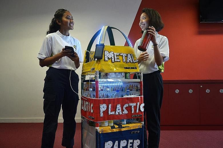 ITE students Nur Afaf Rusydah Mohammad Taha (left) and Nur Asyura Sallehodin demonstrating how their recycling bin works.