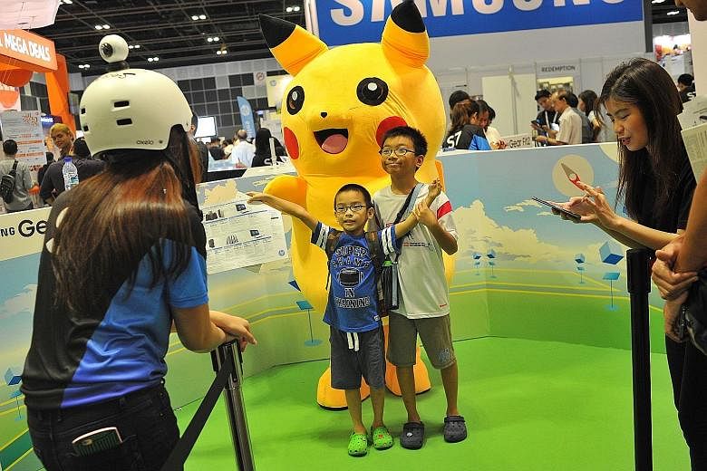 Optimus Seah (in blue), six, and Remus Seah, 10, posing for a photo yesterday with a Pikachu mascot at the Samsung booth, which is promoting the Samsung Gear360.