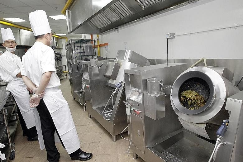 Chefs waiting for a cooking robot to finish its work at a Tung Lok outlet. Tung Lok executive chairman Andrew Tjioe says it takes just one person to operate two robotic cooking machines that can cook 60kg of food for the restaurant chain.
