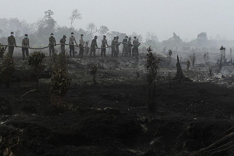 Members of the Indonesian police and military extinguishing a forest fire in Kampar, Riau province, on Aug 29.