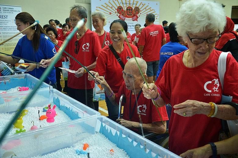 Toa Payoh resident Lim Weng Zuan (second from right), 91, and his helper, Ms Supriatin, trying their hand at a fishing game during a carnival yesterday at the Toa Payoh Sports Hall. Mr Lim was among some 400 seniors who took part in the event organis