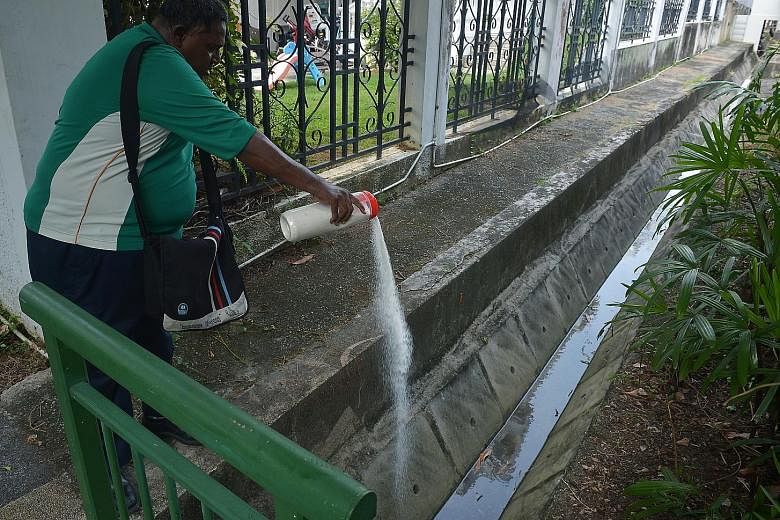 National Environment Agency officers putting granular pesticides in stagnant water in Siglap on Thursday. Ministers Gan Kim Yong and Masagos Zulkifli will speak on the spread of Zika when Parliament sits on Tuesday.