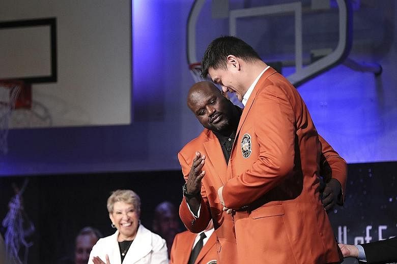 Fellow inductee Shaquille O'Neal helps Yao Ming put on his Hall of Fame jacket during Friday's Basketball Hall of Fame enshrinement ceremony at Springfield Symphony Hall in Massachusetts.
