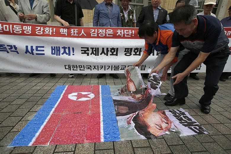 Demonstrators in Seoul yesterday with placards that read "Down with Kim Jong Un, Eliminate North Korean nuclear programme!". The North's latest nuclear test has drawn widespread condemnation. South Korean protesters in Seoul yesterday tearing up post