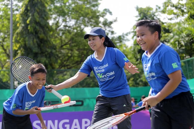 Former world No. 19 Yayuk Basuki (centre) with students Muhammad Rasul (left) and Zakir Zulkarnain (right) at a tennis clinic yesterday. The clinic, featuring 36 children from five primary schools, is part of the SC Global Tennis for Every Child Inter-Sch