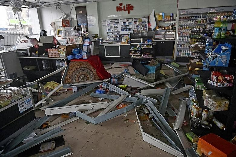 A store in Pingtung county left damaged by yesterday's storm, which was moving east at a speed of about 17kmh and packing winds of up to 227kmh in the late afternoon. A motorist braving fierce winds and rain in Kaohsiung yesterday. Meranti is expecte