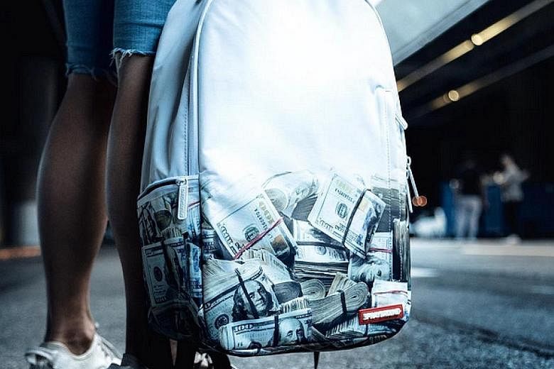 A Sprayground DLX bag emblazoned with stacks of money.