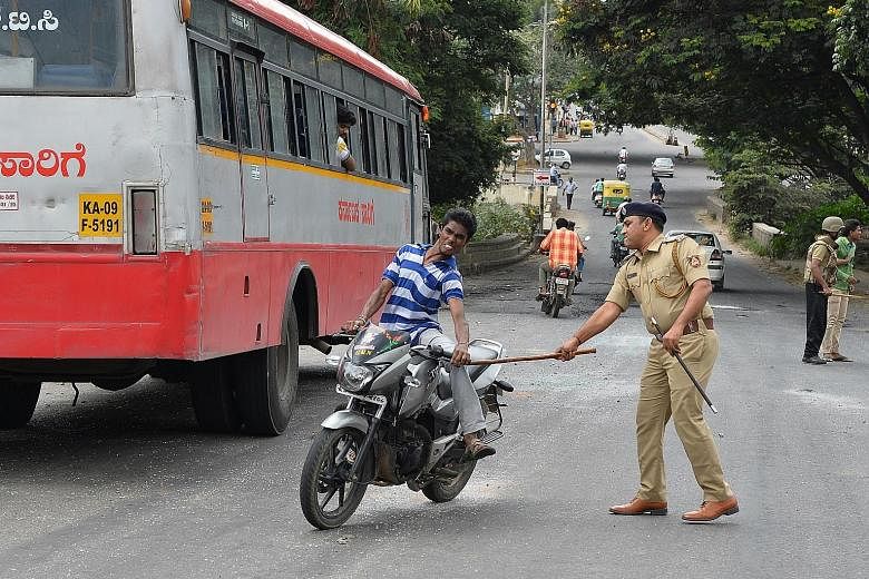 A policeman hitting a motorcyclist during a curfew in Bangalore on Tuesday. Violent protests erupted over the sharing of water from the Cauvery river.