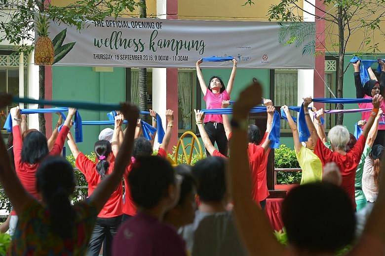 Residents taking part in a mass morning exercise during the official opening of a wellness kampung at Block 765 in Nee Soon Central yesterday. The kampung aims to get people to adopt healthier lifestyles through activities such as healthy cooking dem