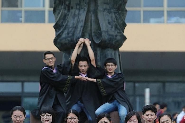 College graduates posing beside a statue of ancient Chinese philosopher Confucius at Qingdao University in eastern China. The broadening of access to university in China is undermining the quality of education.