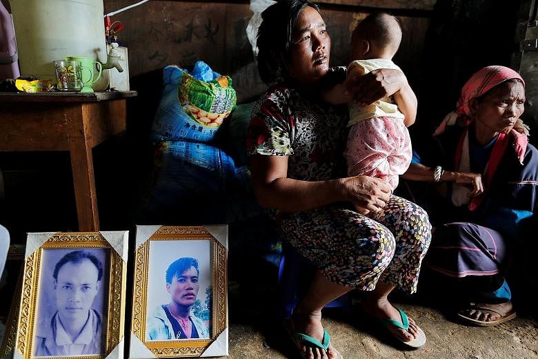 The grieving family members with two of the Mong Yaw victims' pictures in the village in Myanmar's northern Shan state in July. The two men's bodies were among five pulled from shallow graves and identified as missing villagers, after soldiers entere
