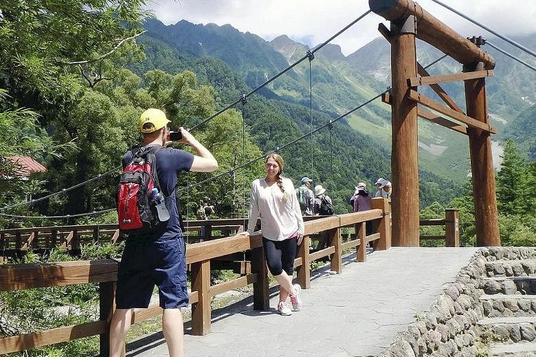 Tourists taking photos near the Kappabashi bridge in the Kamikochi district of Matsumoto, Nagano Prefecture, on July 22. The expansion of foreign tourism has helped change attitudes in Japan towards foreigners.