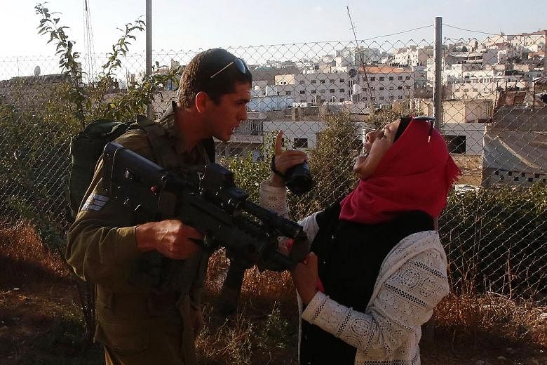 An Israeli soldier scuffling with a Palestinian woman, who was trying to film the scene of a stabbing attack by a Palestinian teenager on an Israeli soldier in Hebron, West Bank, on Friday. The 15-year-old attacker was shot to death, while the soldie
