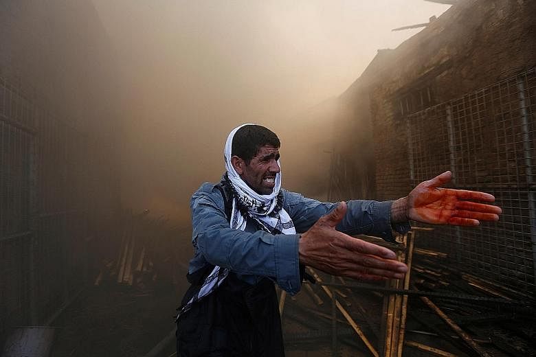 A police officer trying to communicate with firefighters (not in picture) battling a blaze that broke out at a construction wood market yesterday in Kabul, Afghanistan. Witnesses blamed the fire on carelessness, but the cause was as yet not known. Th