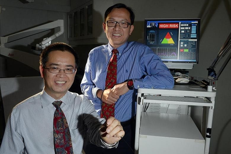 Dr Lim (left) and Prof Huang (far left) of NUS, with the Raman spectroscopy equipment they developed for detecting nose cancer early.