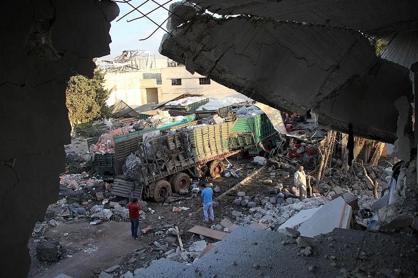 Cargo from aid trucks strewn on the ground in Orum al-Kubra on the outskirts of the northern Syrian city of Aleppo yesterday, the morning after a convoy taking humanitarian assistance to the town was hit by an air strike. The United Nations said at l