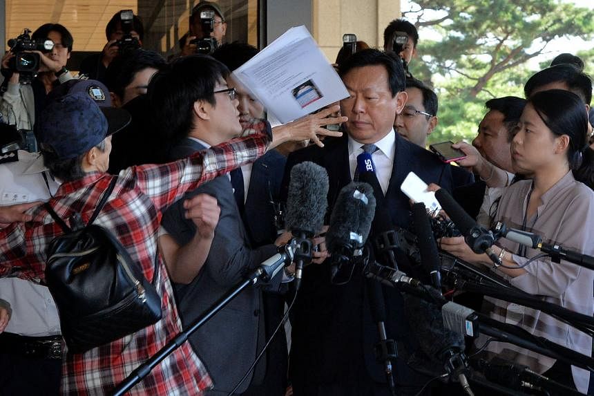 An unidentified man hurling documents at Lotte Group chairman Shin Dong Bin upon his arrival to the prosecutor's office in Seoul yesterday. 