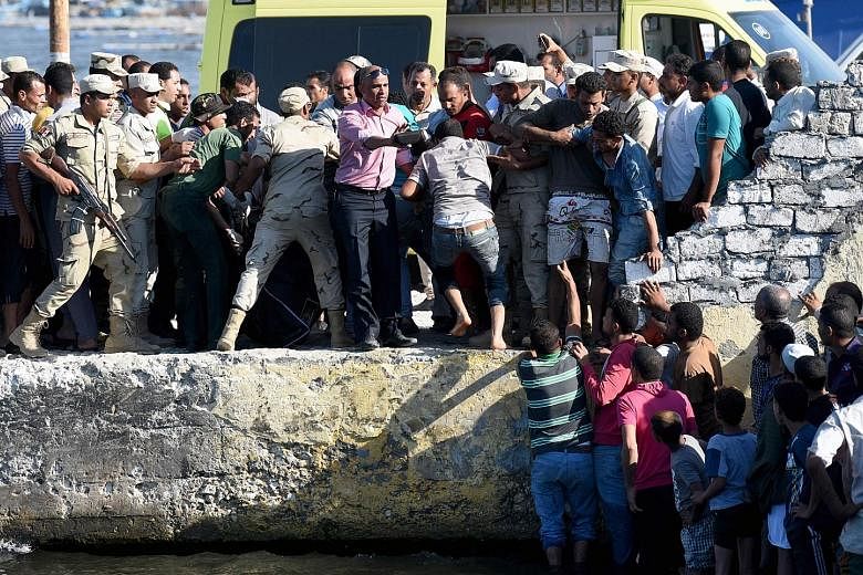 A crowd gathered as the bodies of drowned migrants were brought to shore in the Egyptian city of Rosetta on Wednesday.