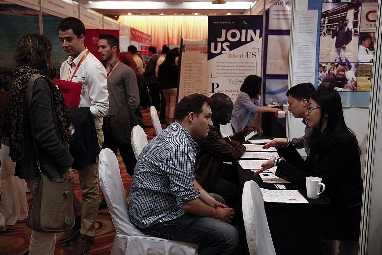 Job seekers talking to company representatives during a job fair for foreigners at a hotel in Beijing in April. The new work permit system is scheduled to be implemented nationwide on April 1 after being tested in nine cities and provinces, including