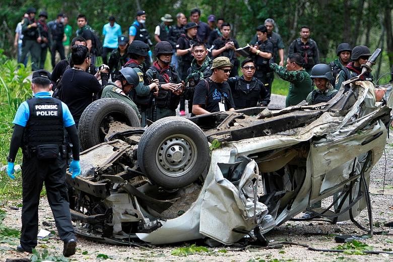 Members of the military inspecting the site of the roadside bomb attack in Krong Pinang district in the southern province of Yala, Thailand, yesterday.