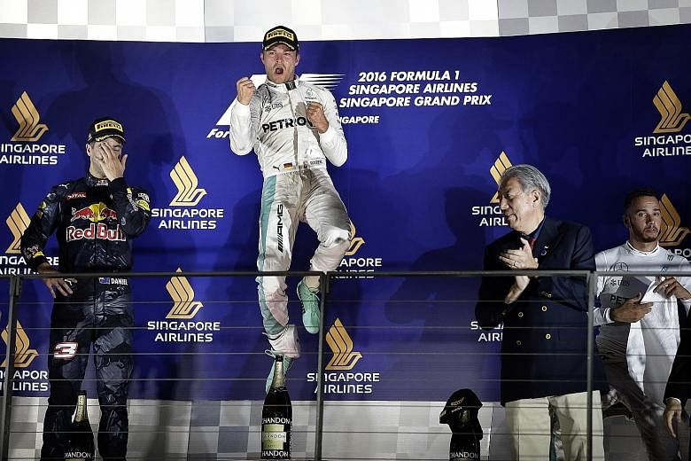Mercedes driver Nico Rosberg celebrating after winning the Singapore night race, with his dejected-looking team-mate and title rival Lewis Hamilton third and Red Bull's Daniel Ricciardo second.