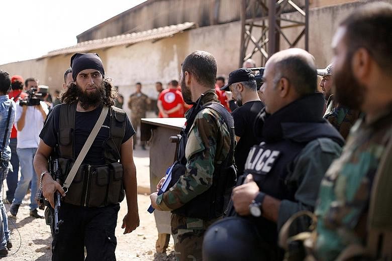 A rebel fighter (left) next to Syrian army soldiers, prior to evacuating the besieged Waer district in the central Syrian city of Homs, after a local agreement was reached between rebels and Syria's army on Thursday.
