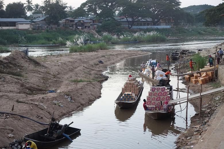 Young Myanmar workers cross the Moei River daily looking for work in the Thai district of Mae Sot on the border with Myanmar, which can be seen in the background. The construction of special economic zones along the border between the two countries is und