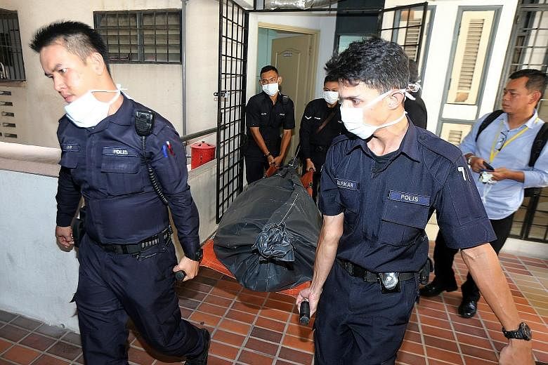 Police carrying Mr Cheah's body out of the apartment in Kuala Lumpur. His estranged wife has been arrested over his murder as well as that of two of their children.