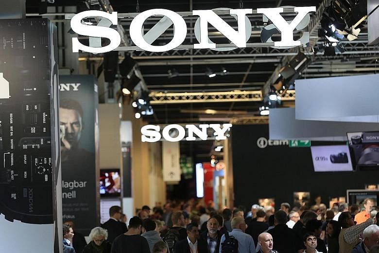 Visitors browsing a display containing a selection of Canon camera lenses during the Photokina photography trade fair in Cologne on Sept 20. At the Photokina photography trade fair, Sony unveiled&#97; the the &#97;99 II, the long-awaited successor to