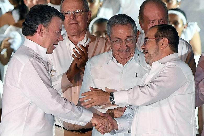 Colombian President Juan Manuel Santos (left) and Farc leader Timoleon "Timochenko" Jimenez (right) shaking hands as Cuban President Raul Castro looked on after the signing of the peace agreement in Cartagena on Monday.