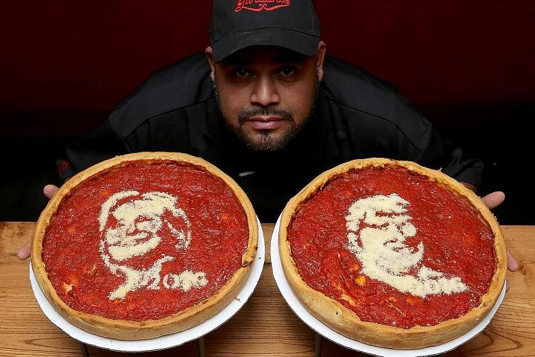 Head cook Fabian Martinez poses with pizzas decorated with the images of Mrs Clinton and Mr Trump at Giordano's Pizzeria in Chicago.