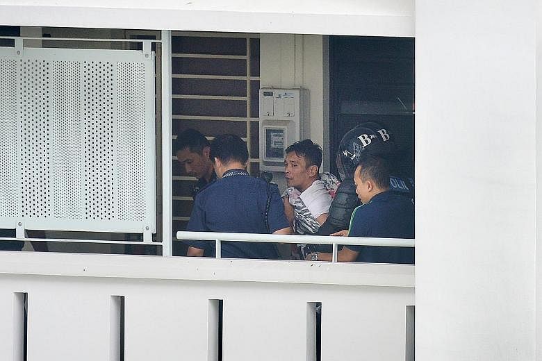 Police yesterday leading away the 39-year-old man (left), who had locked himself in the Sembawang unit (above) with his girlfriend's two-year-old son. The unarmed man was arrested for wrongful confinement and drug-related offences, and the boy is now