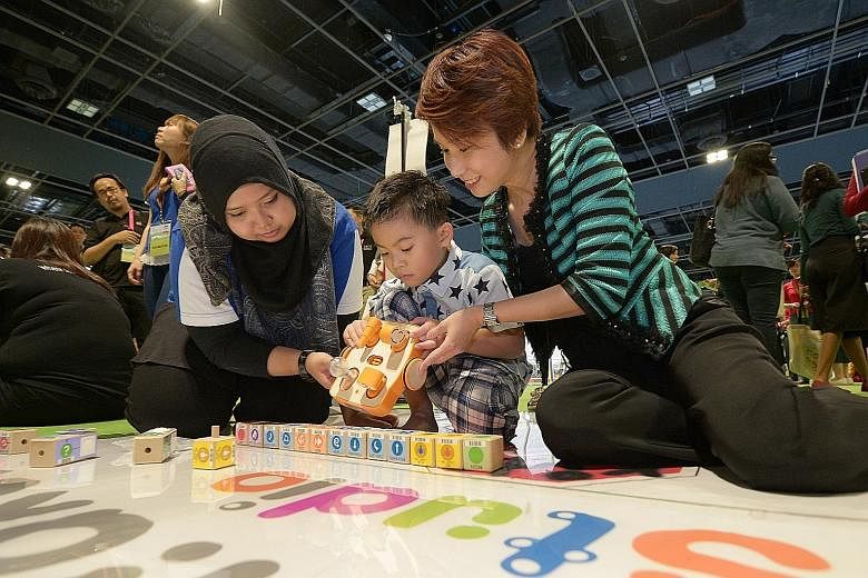 Parliamentary Secretary for Education Low Yen Ling (far right) joining six-year-old Teo Cheng Wei as he plays with Kibo, a robot programmed to move according to action commands recorded by scanning the blocks.