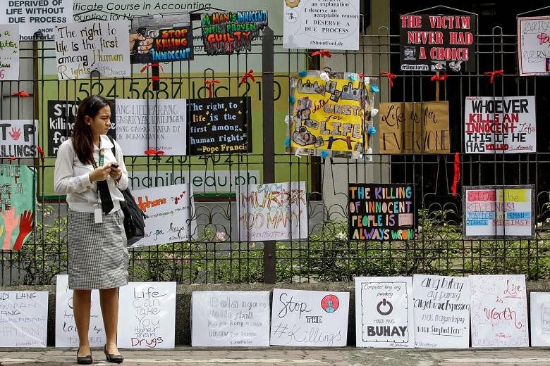A Filipino student in front of placards at her school during a protest against drug-related killings in Manila yesterday. More than 3,000 people have been killed in a crackdown over the past three months.