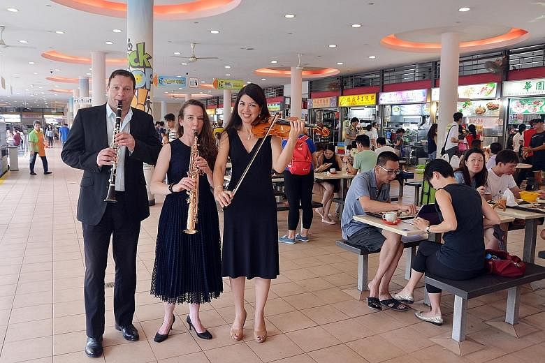 Visitors to Tiong Bahru market yesterday were greeted by an unusual sight - members of the Australian World Orchestra going around taking photographs with curious residents. Among the musicians were (from left) clarinetist Frank Celata, saxophonist C