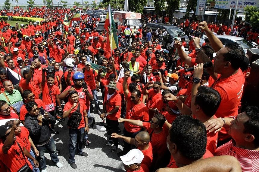 Bersih members (left) drumming up support for their movement in Gelang Patah, Johor yesterday while an anti-Bersih group dressed in red shirts (above) hold their own demonstration in Penang.