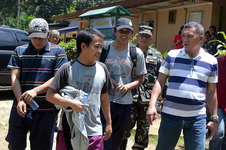 The three Indonesian sailors (from left), accompanied by soldiers and local officials, after their release by Abu Sayyaf rebels yesterday.